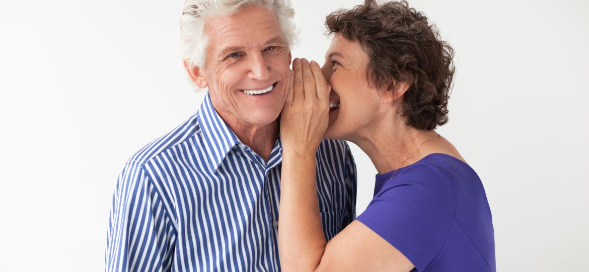 Elderly Woman Whispering Secret to Smiling Husband